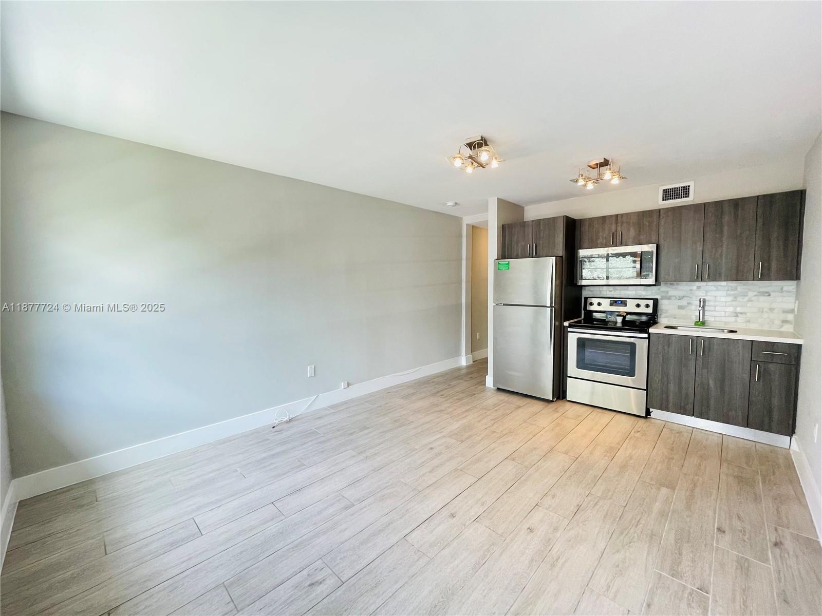 1100 10th Street, Unit 7 Miami Beach, FL 33139 - Photo 5 of 6 a kitchen with granite countertop a refrigerator and a stove top oven