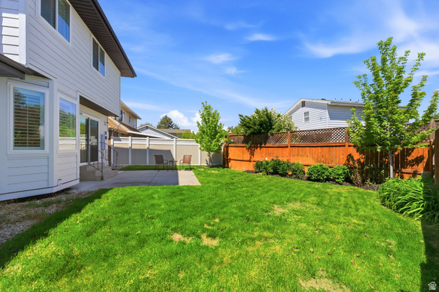 1405 Vintry Lane Murray, UT 84121 - Photo 35 of 44 Expansive backyard featuring a manicured lawn, concrete patio, and a combination privacy fence