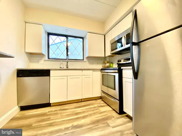 a kitchen with stainless steel appliances a stove a sink and white cabinets