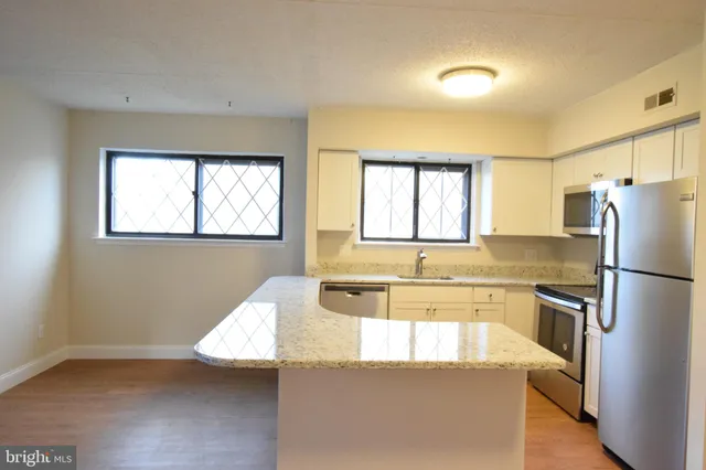 a kitchen with granite countertop a refrigerator a sink a stove and island