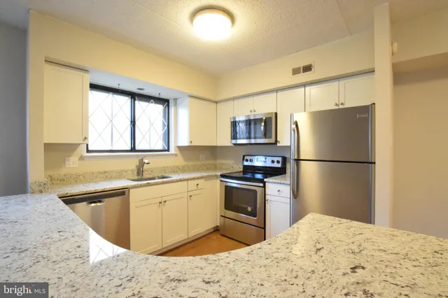 a kitchen with stainless steel appliances granite countertop a refrigerator sink stove microwave and cabinets