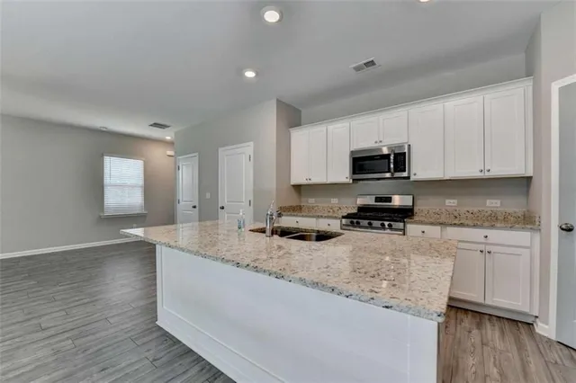a kitchen with granite countertop a sink cabinets and wooden floor