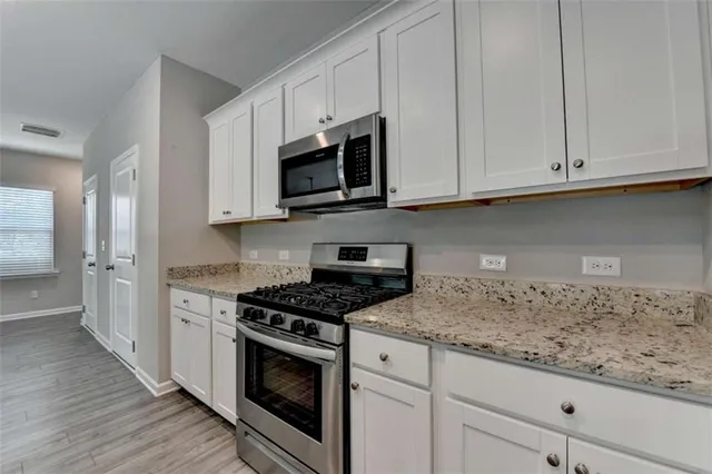 a kitchen with granite countertop white cabinets and stainless steel appliances