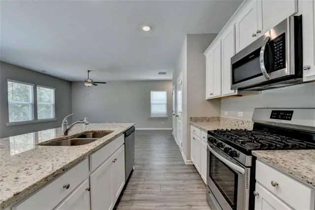 a kitchen with stainless steel appliances granite countertop a sink stove and microwave