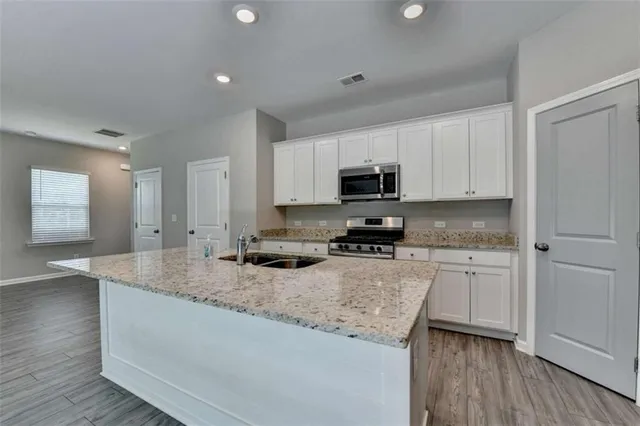 a kitchen with stainless steel appliances granite countertop a sink a stove and cabinets