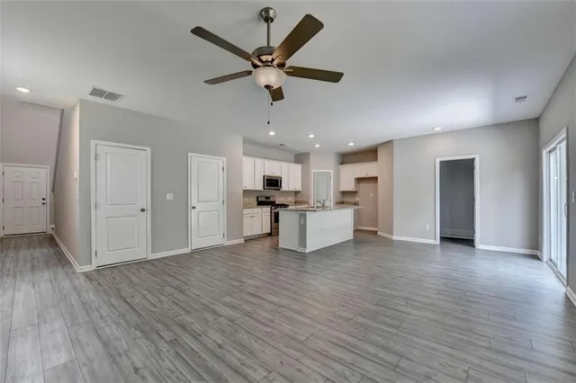 a view of a big room with wooden floor and a kitchen