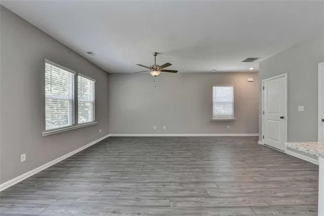 a view of an empty room with a window and wooden floor