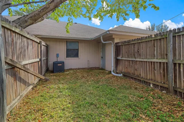 a view of backyard with small garden and wooden fence