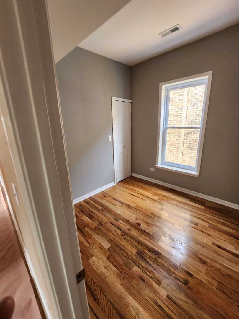 Undisclosed Address Chicago, IL 60624 - Photo 11 of 27 a view of empty room with wooden floor and fan