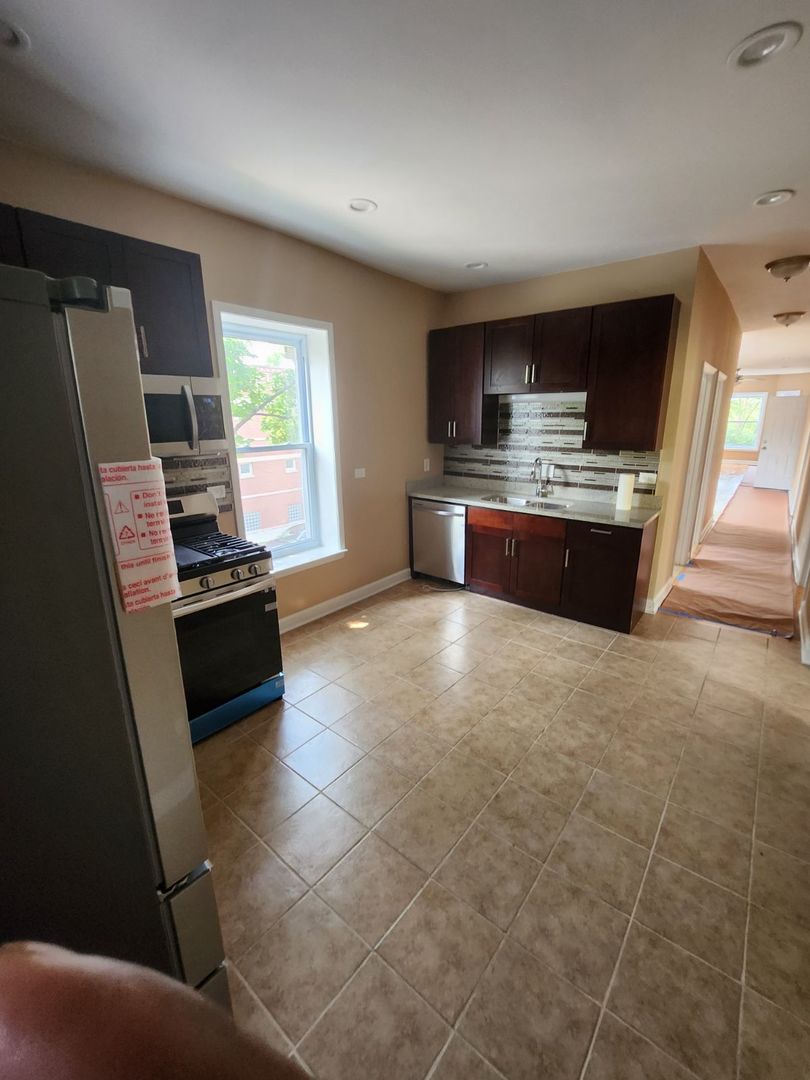 Undisclosed Address Chicago, IL 60624 - Photo 12 of 27 a large kitchen with a stove a sink dishwasher and a stove top oven