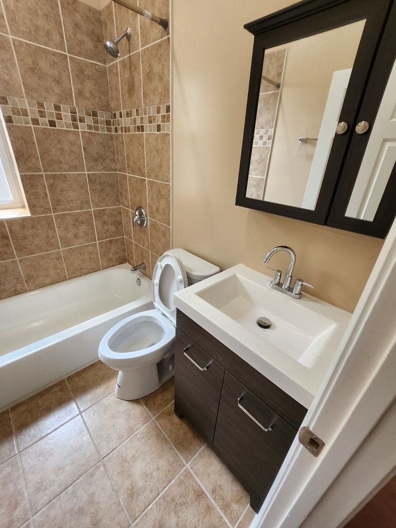 Undisclosed Address Chicago, IL 60624 - Photo 14 of 27 a bathroom with a sink toilet a mirror and bathtub