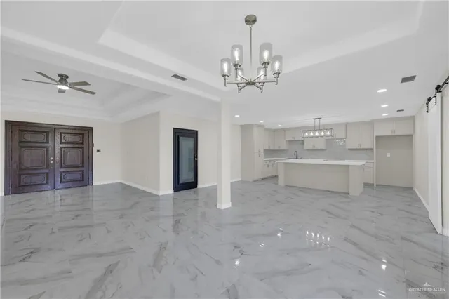 a view of a hallway with a chandelier and a kitchen