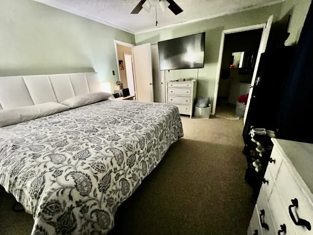 a bedroom with a bed and a flat tv screen on dresser