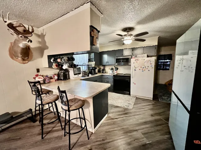 a kitchen with stainless steel appliances kitchen island granite countertop a table chairs and a refrigerator