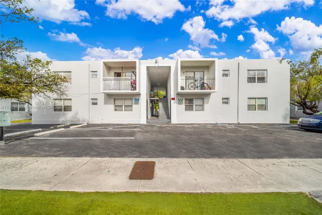 a view of a white building with a yard
