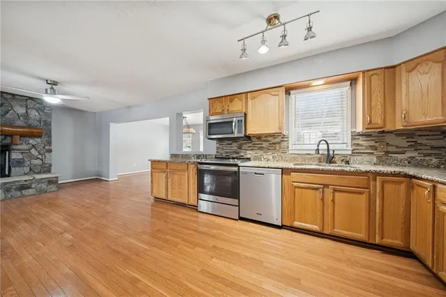 a kitchen with stainless steel appliances granite countertop a stove a sink and a granite counter tops with white cabinets