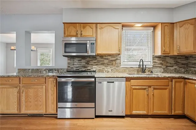a kitchen with stainless steel appliances granite countertop a sink a stove and cabinets