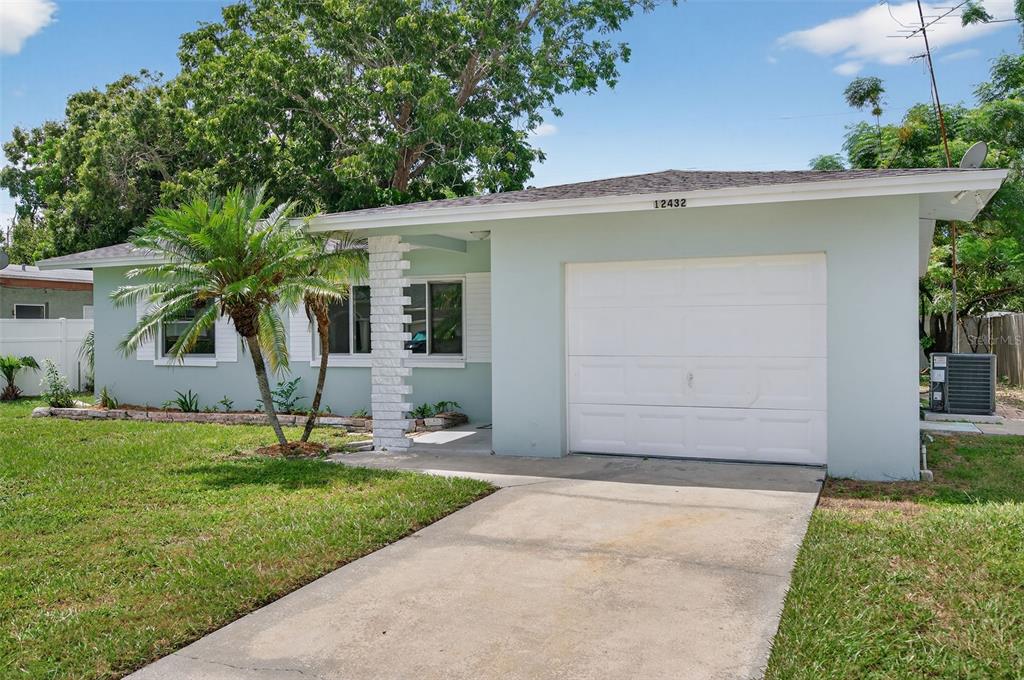 12432 136th Lane Largo, FL 33774 - Photo 2 of 64 a front view of a house with a yard and garage