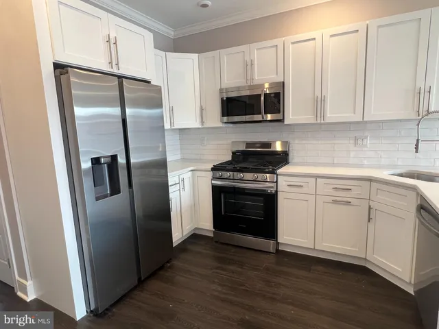 a kitchen with white cabinets and stainless steel appliances