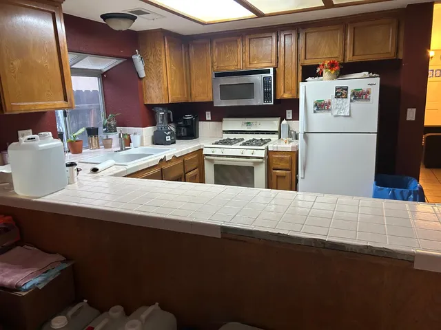 a kitchen with granite countertop a refrigerator stove top oven a sink and dishwasher