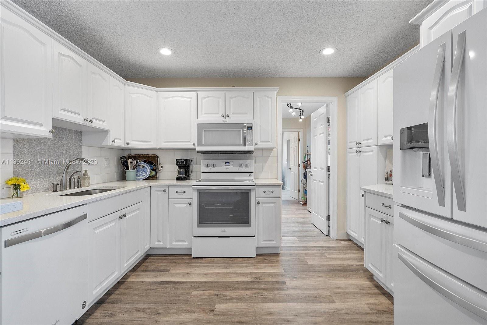 19404 Colorado Circle Boca Raton, FL 33434 - Photo 14 of 62 a kitchen with white cabinets and stainless steel appliances