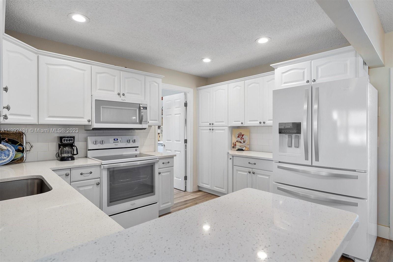 19404 Colorado Circle Boca Raton, FL 33434 - Photo 17 of 62 a kitchen with white cabinets and stainless steel appliances