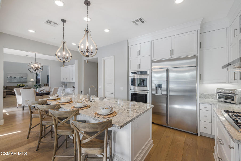 13148 Bent Grass Place Moorpark, CA 93021 - Photo 20 of 76 a kitchen with kitchen island a dining table chairs stainless steel appliances and cabinets