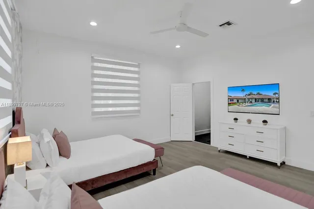 a view of a white house with swimming pool lawn chairs and palm chairs