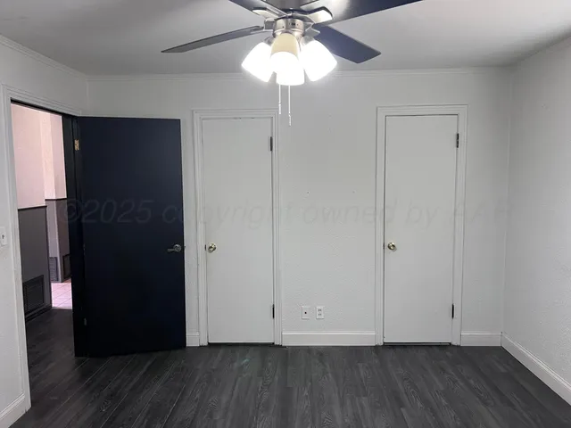 an empty room with windows and fan