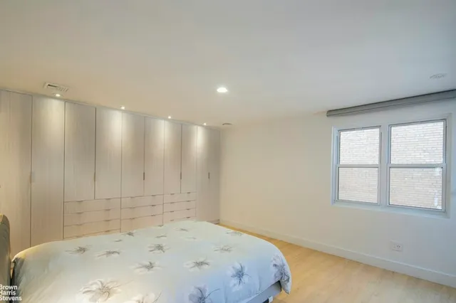 a view of a bedroom with wooden floor and window