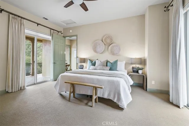 a bedroom with a large bed and a chandelier fan