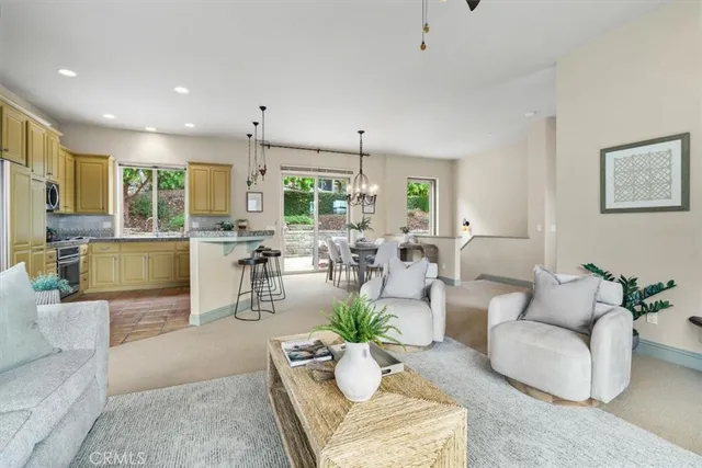 a living room with furniture potted plant kitchen view and a window
