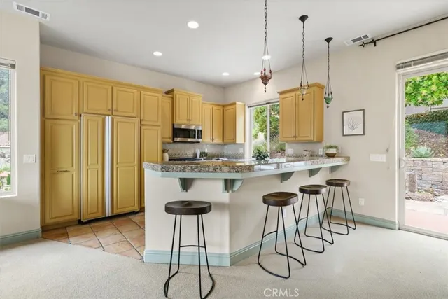 a kitchen with stainless steel appliances granite countertop a refrigerator a sink dishwasher a dining table and chairs with wooden floor