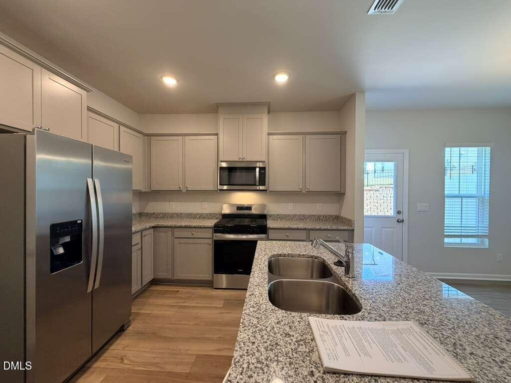 5024 Reader Way Durham, NC 27703 - Photo 7 of 26 a kitchen with granite countertop a refrigerator stove and sink