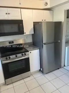 a kitchen with stainless steel appliances a refrigerator a stove and white cabinets