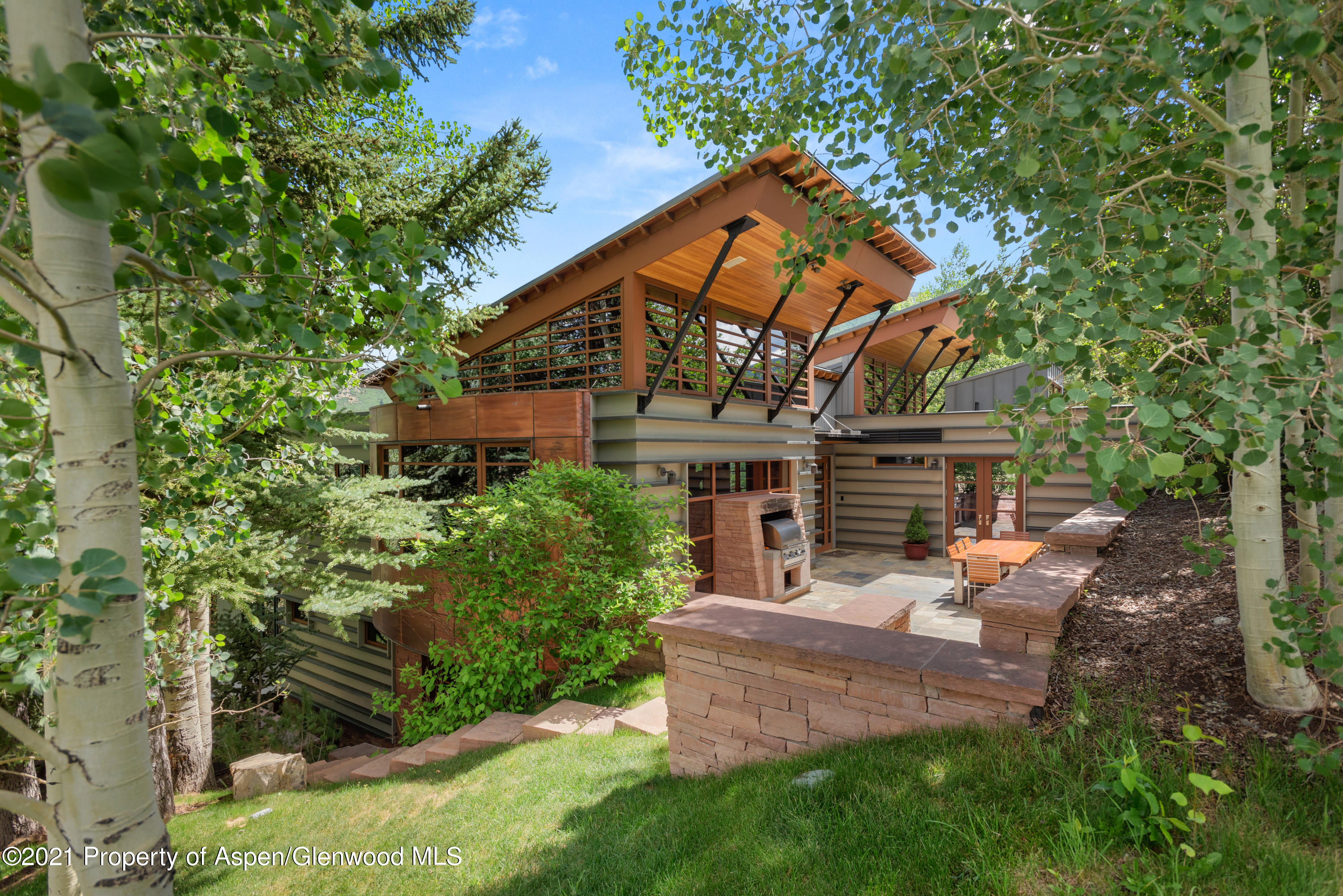 550 Aspen Alps Road South Aspen, CO 81611 - Photo 4 of 58 a backyard of a house with table and chairs under an umbrella