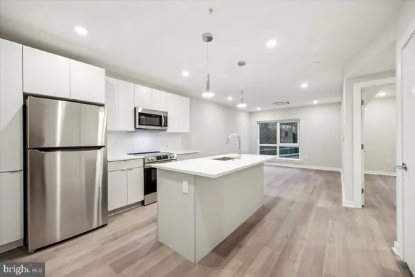 a kitchen with stainless steel appliances granite countertop a refrigerator a stove a sink dishwasher and a refrigerator with wooden floor