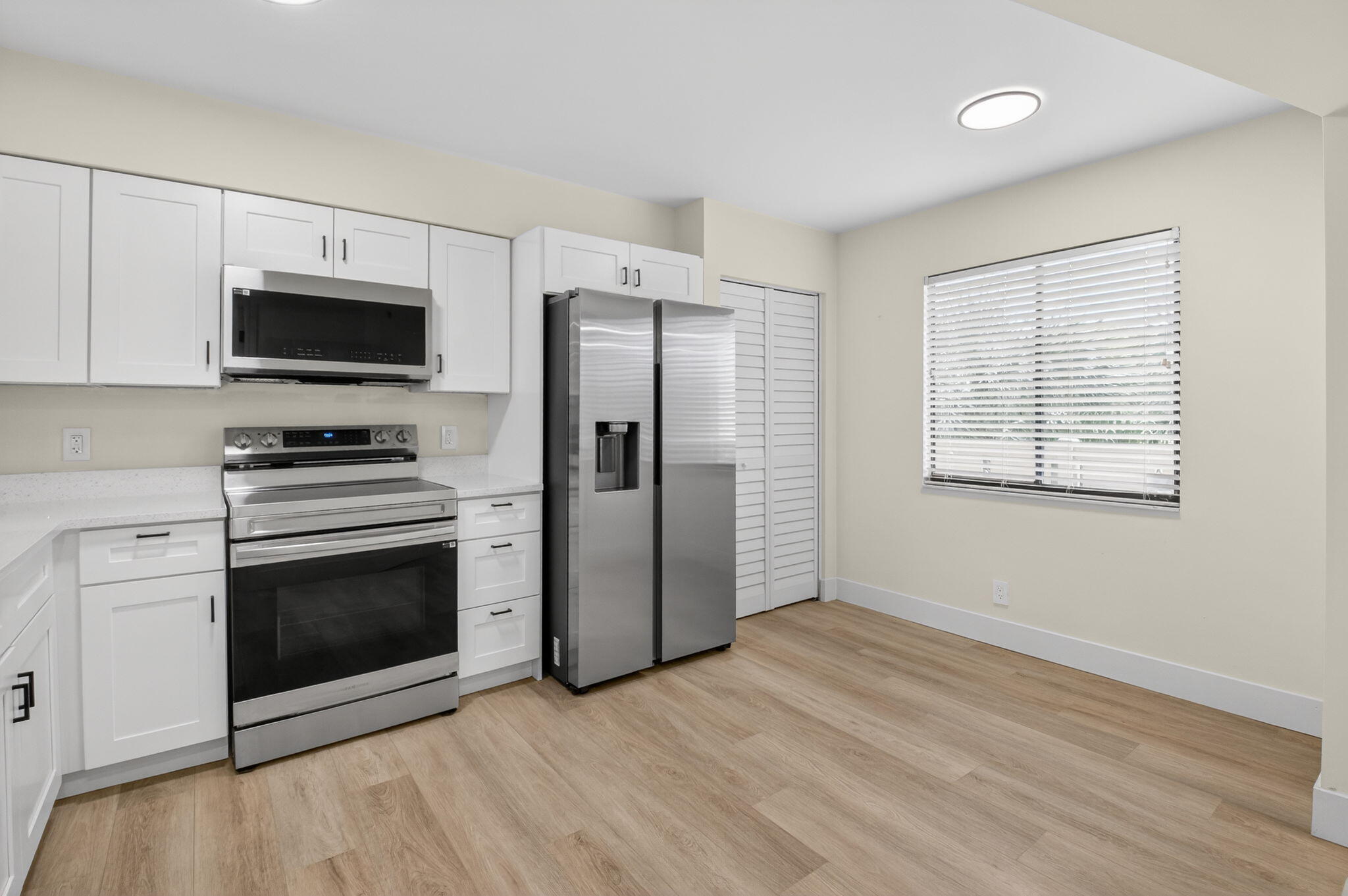 14475 Strathmore Lane, Unit 305 Delray Beach, FL 33446 - Photo 4 of 27 a kitchen with granite countertop a refrigerator and a stove top oven