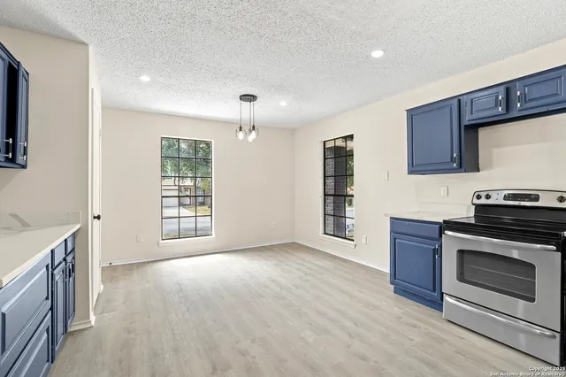 a view of an empty room with a kitchen and a window