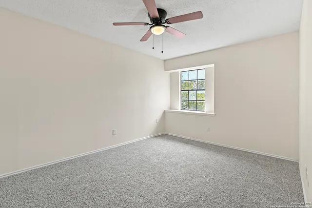 an empty room with a window and a fan