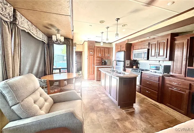 a living room with stainless steel appliances granite countertop furniture a rug kitchen view and a window