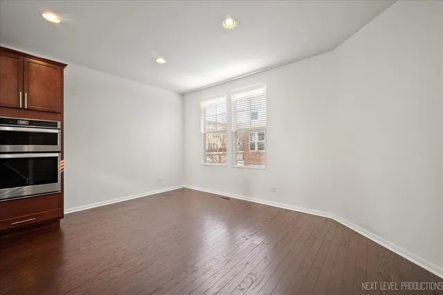 an empty room with wooden floor closet and windows