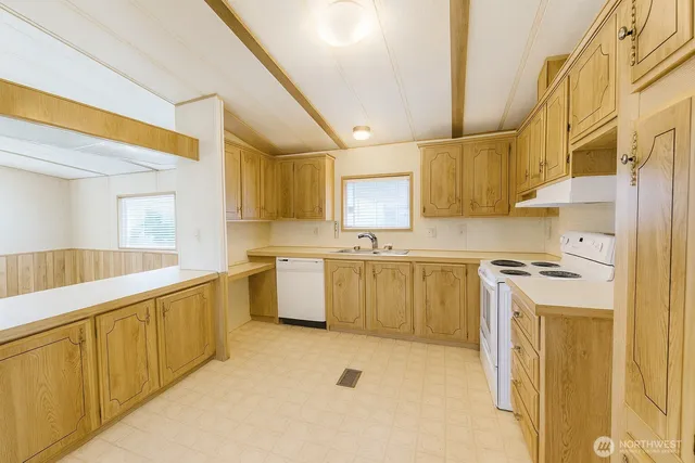a kitchen with cabinets a sink and white appliances