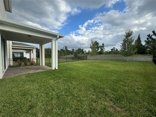 a view of a house with a big yard potted plants and large tree