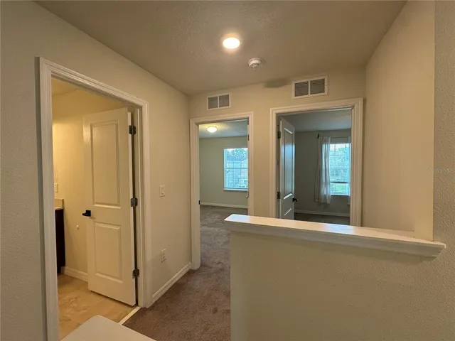 a view of a hallway with wooden floor and a bathroom