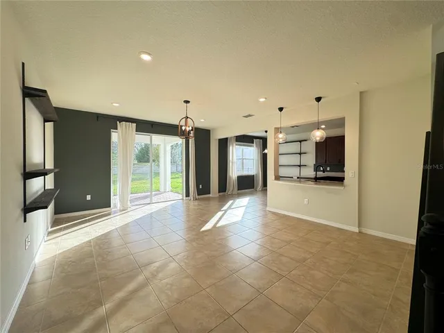 a view of an empty room with kitchen and a window