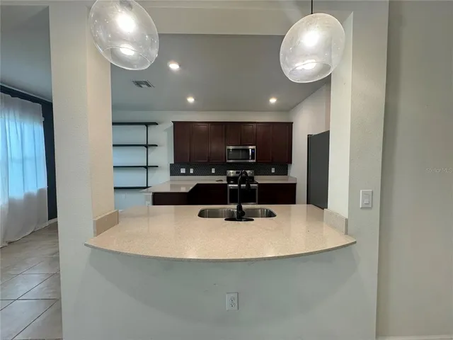 a kitchen with kitchen island stainless steel appliances a sink and cabinets