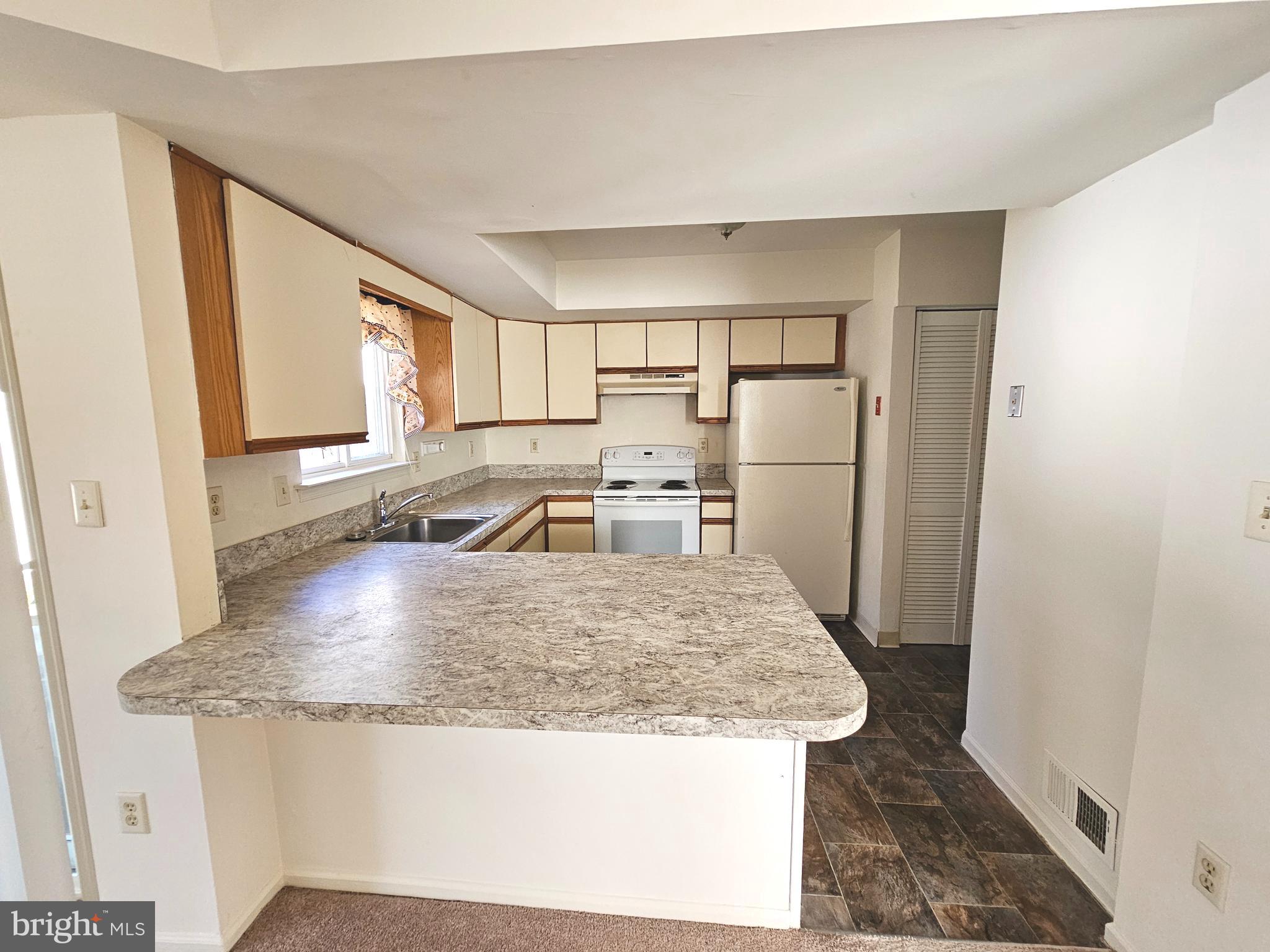 38 Heatherfield Way Dover, DE 19904 - Photo 8 of 26 a kitchen with granite countertop a refrigerator a sink a stove and white cabinets