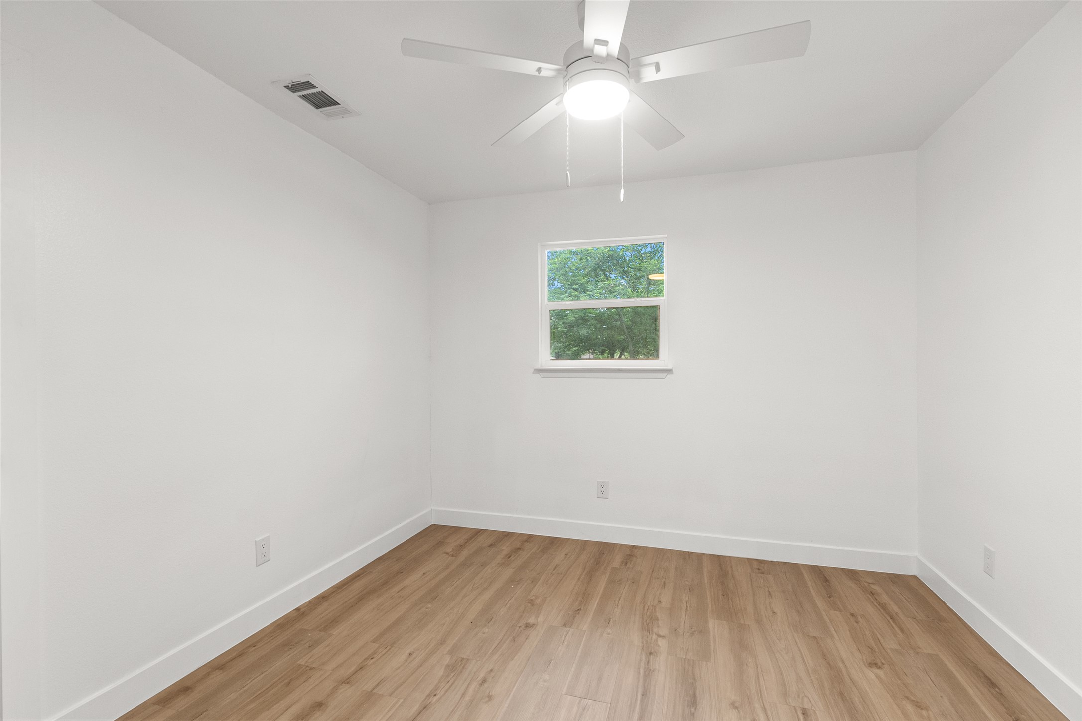 409 Ave R Marble Falls, TX 78654 - Photo 22 of 25 Bright room featuring wood-finish flooring, white walls, and a ceiling fan with integrated lighting