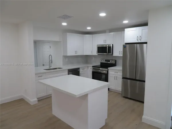 a kitchen with a refrigerator a stove top oven and a sink